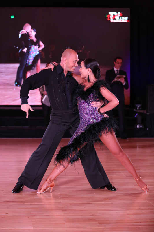 A man and a woman in dramatic dance pose, facing one another 